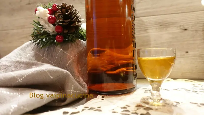 Liquore genziana ricetta: bottiglia ambrata, bicchierino dorato e decorazione natalizia.