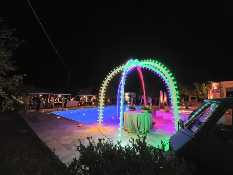 Serata magica con luci colorate, piscina illuminata e un'atmosfera da sagre di paese.