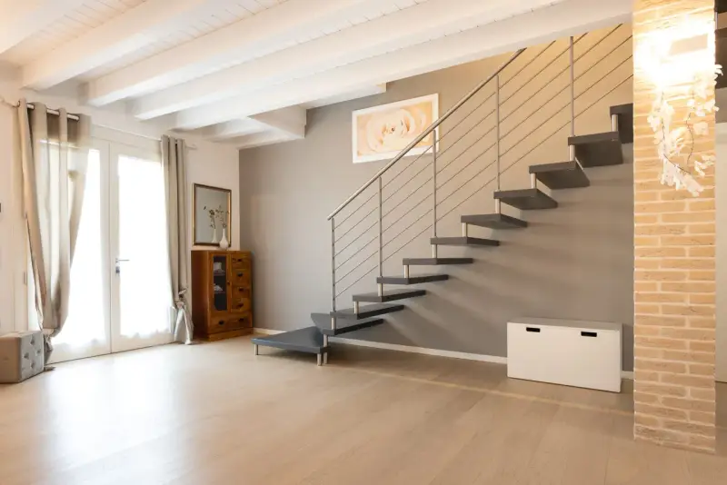 Moderna scala a sbalzo, soluzione per chi ha una scala troppo ripida. Arredamento minimalista con mobili in legno e tessuti chiari.