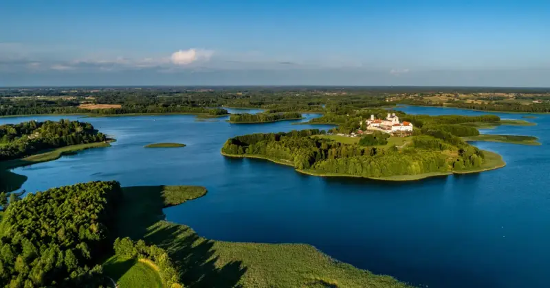 Malowniczy wschód Polski nad jeziorem, z wyspą i klasztorem.