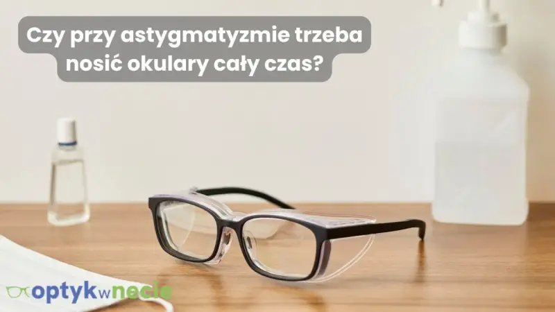 Okulary ochronne na drewnianym blacie, obok płynu do dezynfekcji i maseczki. Czy przy astygmatyzmie trzeba nosić okulary cały czas?