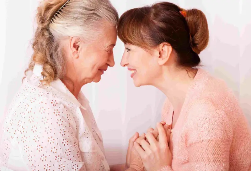 Un abbraccio tra madre e figlia, un momento di affetto che può aiutare a gestire i sintomas de alzheimer, con mani che si stringono.