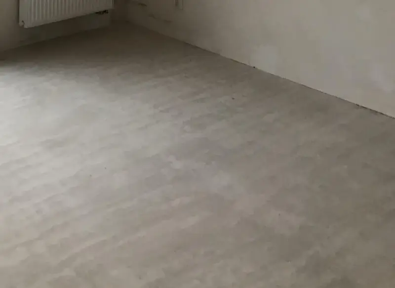 Świeżo wylana, szara krzywa wylewka samopoziomująca na podłodze, gotowa na dalsze prace wykończeniowe.