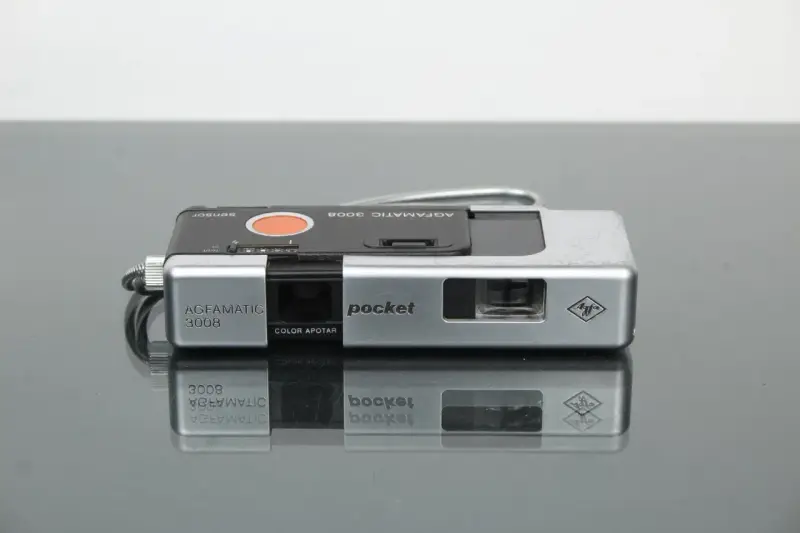 Srebrny aparat Agfamatic 3008 z napisem "pocket" i logo Agfa. Idealny do uchwycenia wspomnień.