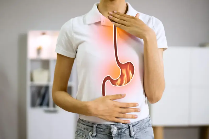 Persona con bruciore di stomaco, illustra la differenza tra pantoprazolo e omeprazolo per alleviare il disturbo.