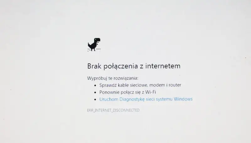 Dinozaur z gry Chrome skacze, bo jest brak internetu. Komunikat "Brak połączenia z internetem" sugeruje sprawdzenie kabli i ponowne połączenie z Wi-Fi.