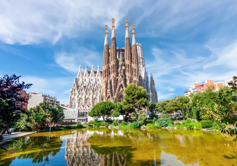 La Sagrada Familia, con le sue torri svettanti e il riflesso sull'acqua, sembra un sogno che attende il suo completamento. Chissà quando finirà la Sagrada Familia.