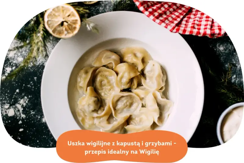 Pyszne uszka z grzybami, idealne na Wigilię, podane w białej misce, ozdobione gałązkami choinki i plasterkiem cytryny.