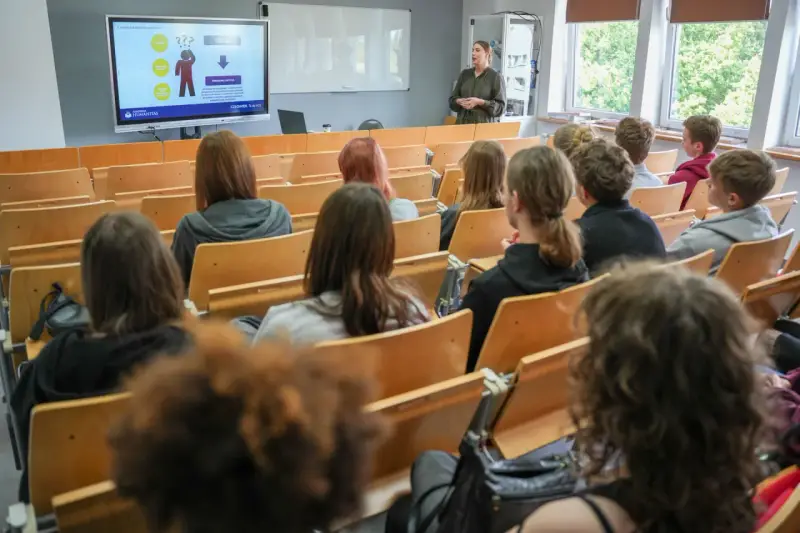 Wykład o przygotowaniu pedagogicznym dla psychologów. Studenci słuchają prelegentki przy tablicy interaktywnej.