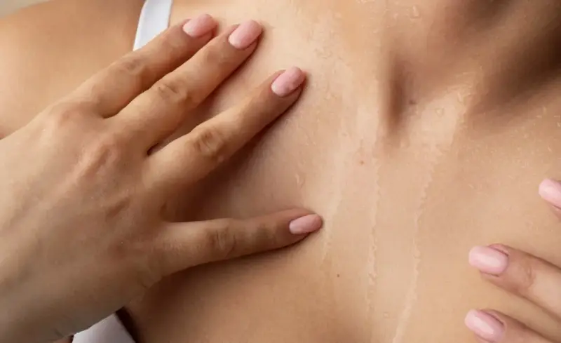 Mani accarezzano la pelle naturale cos'è: idratata e luminosa, con goccioline d'acqua che riflettono la luce.