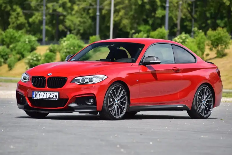 Czerwone BMW f23 coupe z czarnymi dodatkami i felgami stoi na asfalcie.