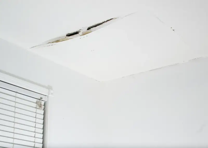 Widoczne pęknięcia na łączeniu sufitu i ściany, świadczące o problemach z konstrukcją lub wilgocią.
