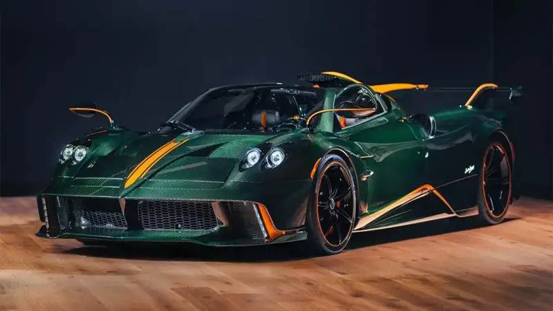 Pagani Huayra w kolorze głębokiej zieleni z pomarańczowymi akcentami, prezentuje swoje karbonowe nadwozie na drewnianej podłodze.