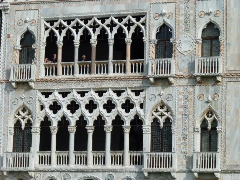 Dettaglio del **Palazzo Cadoro** con le sue finestre a trifora e balconi ornati. Persone osservano dal primo piano.