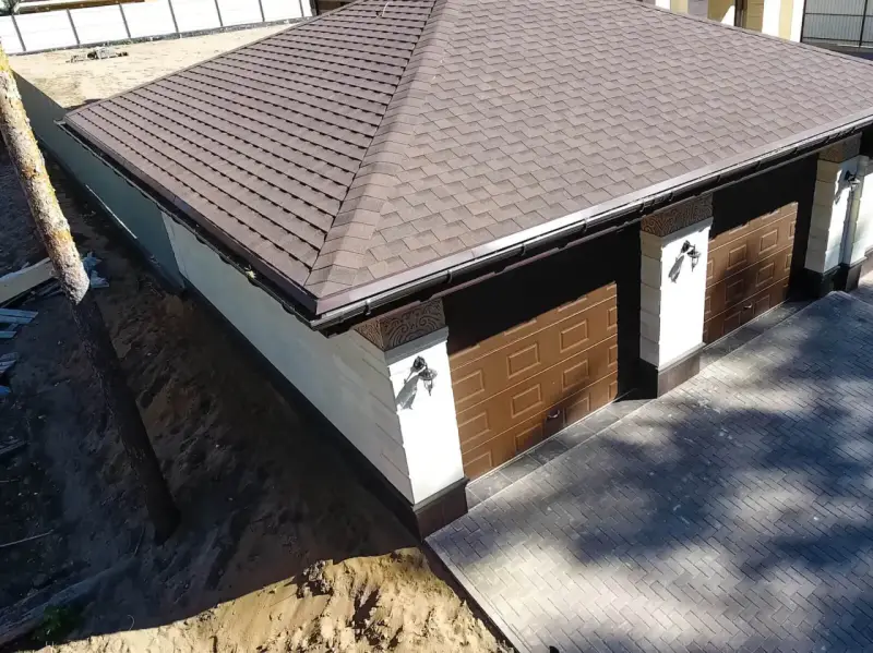 Nowy dach papa na garażu z brązowymi drzwiami i ozdobnymi słupkami.