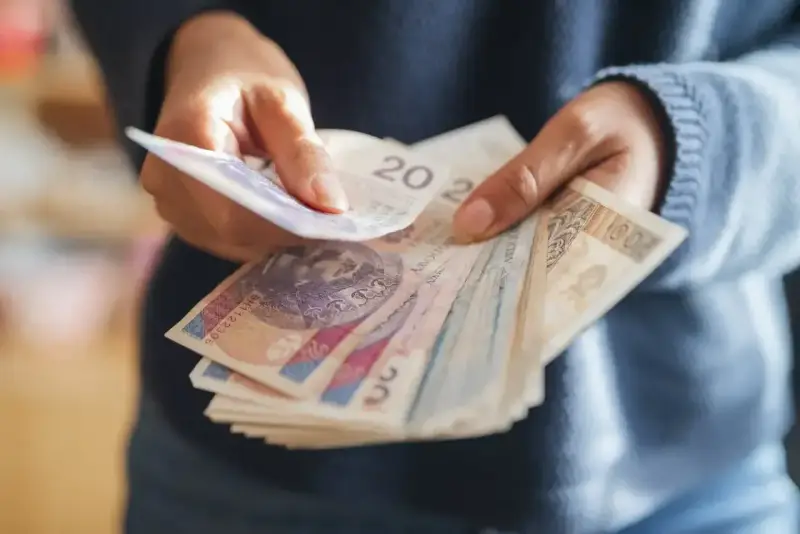 Ręce liczą banknoty, zastanawiając się, co z pieniędzmi z OFE po przejściu na emeryturę.