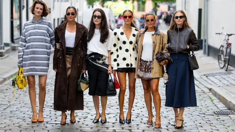 Sechs Frauen präsentieren ihren **scandi look** auf Kopfsteinpflaster. Von gestreiften Kleidern bis zu Lederjacken – ein vielfältiger Stilmix.