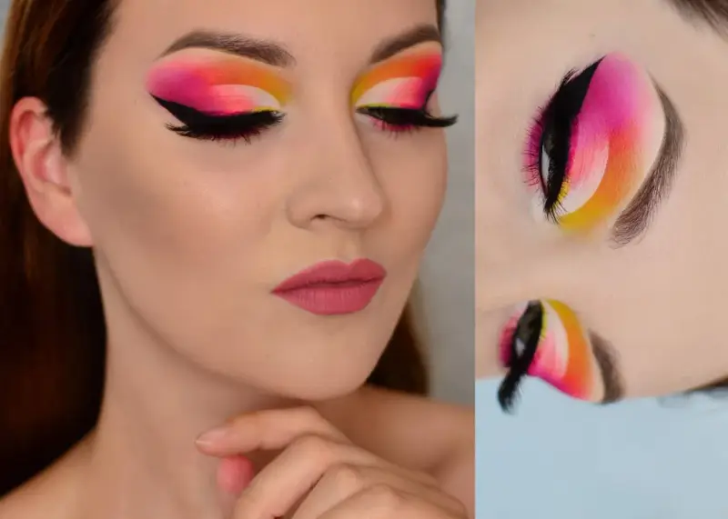 Oczy z wyrazistym makijażem cut crease w odcieniach różu, pomarańczy i żółci. Czarne kreski i długie rzęsy podkreślają spojrzenie.