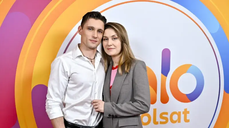 Małgorzata Patryn Gurłacz z partnerem pozują na tle kolorowego logo.
