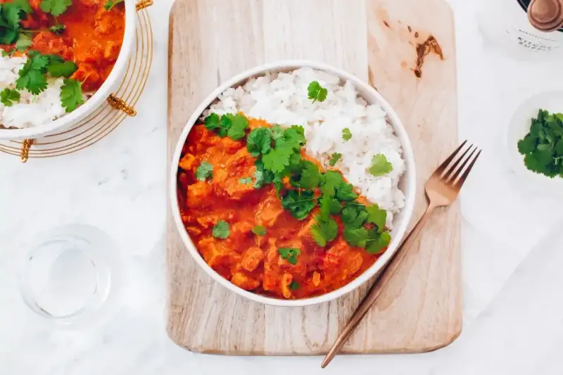 Pyszne czerwone curry z kurczakiem i ryżem, udekorowane świeżą kolendrą. Idealny przepis na obiad.