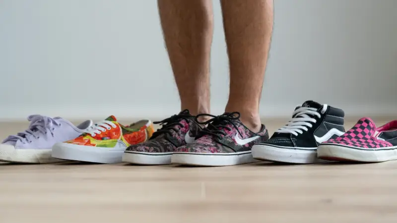 Un hombre elige entre varias zapatillas de **material canvas**. Hay modelos de colores, estampados florales, de cuadros y lisos.