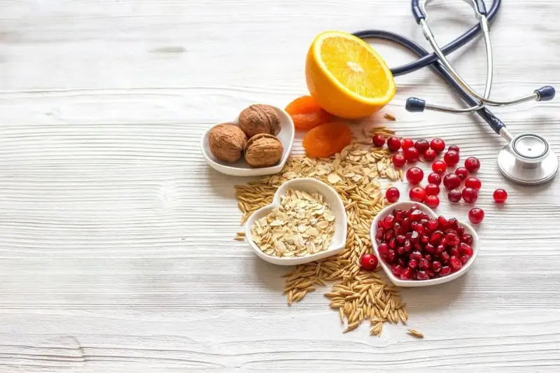 Sposób babci na obniżenie cholesterolu: orzechy, owsianka, żurawina, granat, pomarańcza i suszone morele. Stetoskop symbolizuje zdrowie.