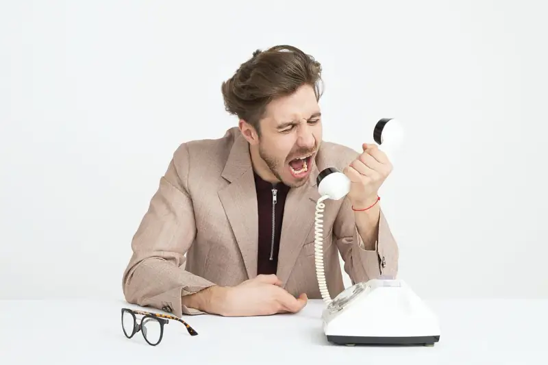 Mężczyzna w garniturze krzyczy do telefonu, jego twarz wyraża złość. Widać, że jest cholerykiem.