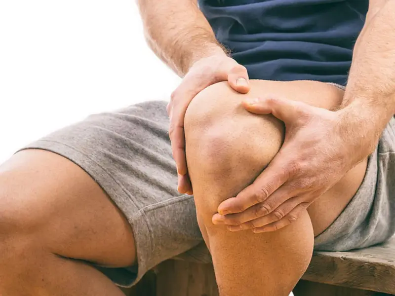 Mann hält schmerzendes Knie. Schmerzen beim Knien auf hartem Boden sind deutlich zu sehen.