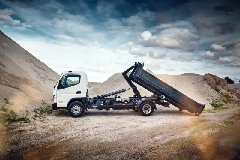 Biały Mitsubishi Canter z podniesioną skrzynią ładunkową na tle żwirowych hałd.