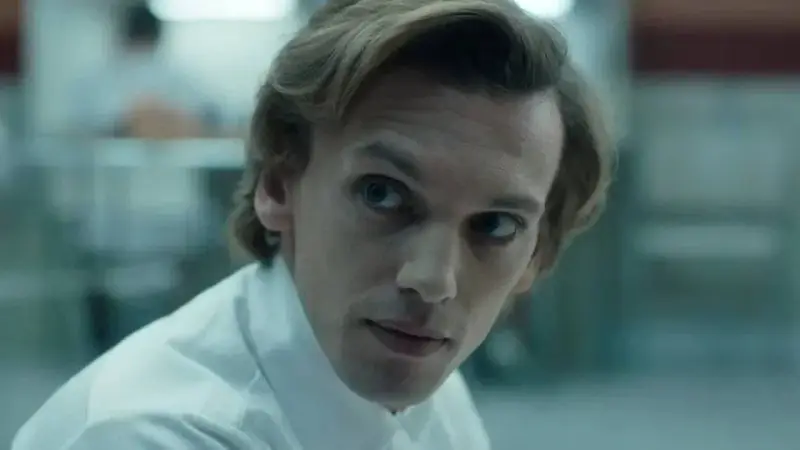 Henry Creel, znany jako Vecna z 001 stranger things, w białej koszuli, patrzy z uwagą.