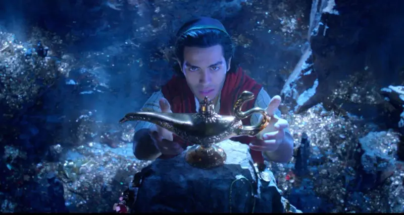 Aladyn, w mrocznej jaskini pełnej skarbów, trzymając magiczną lampę.