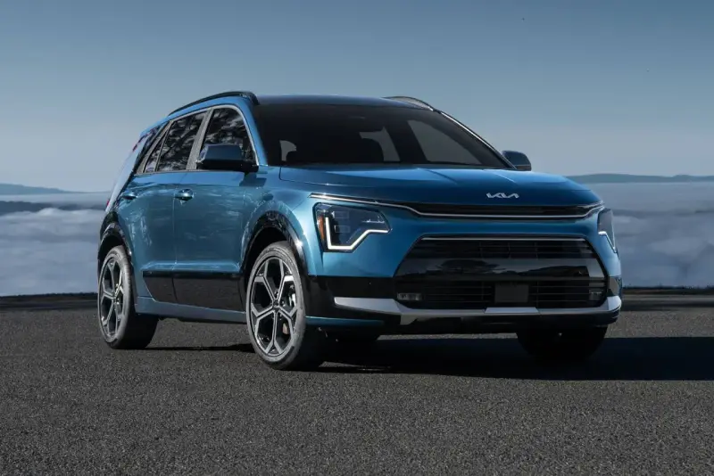 Niebieski Kia Niro Hybrid z nowoczesnym designem, zaparkowany na tle mglistego krajobrazu.