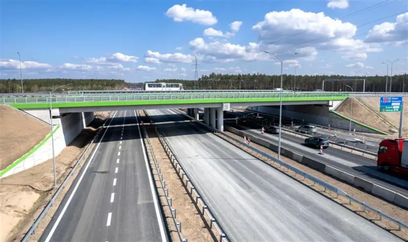 Nowa autostrada A6 z zielonym wiaduktem i ruchem samochodowym.