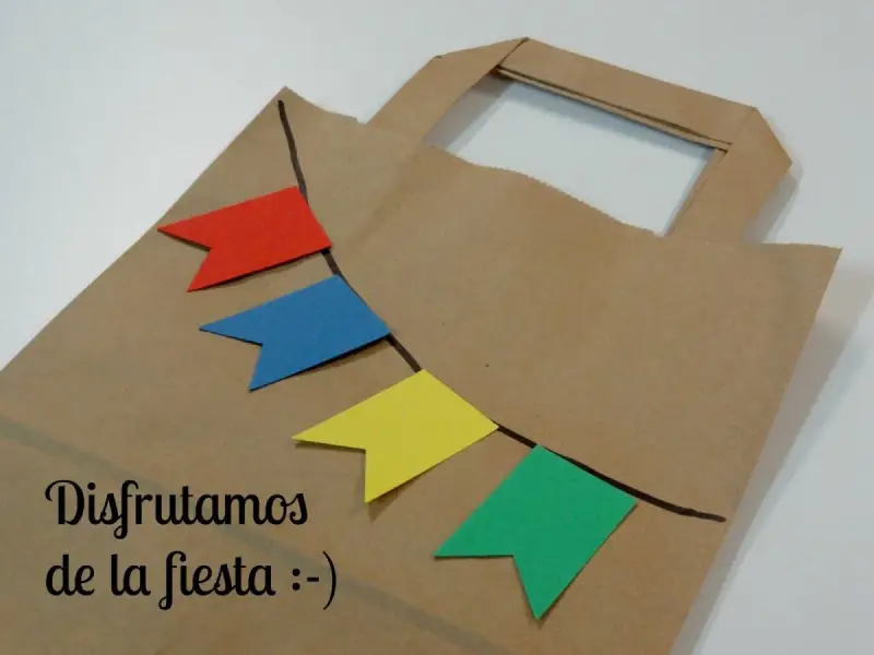 Bolsa de papel decorada con banderines de colores, ideal para hacer bolsas de chuches caseras y disfrutar de la fiesta.