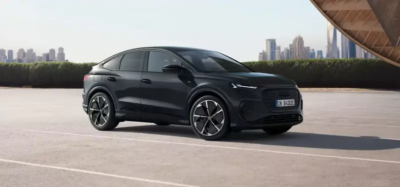 Elegancki, czarny Audi Q4 e-tron, elektryk z dynamiczną linią nadwozia, zaparkowany na tle nowoczesnej panoramy miasta.