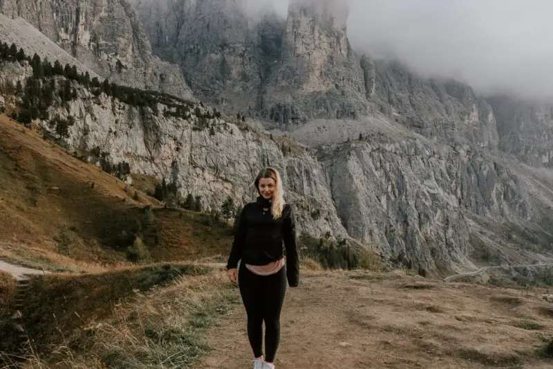 Kobieta na tle majestatycznych gór w Val di Funes. Mgła otula szczyty, tworząc mistyczną atmosferę.