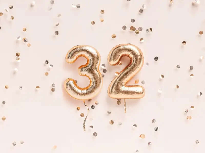 Złote balony z cyframi 3 i 2, otoczone konfetti. To już 32 tydzień ciąży, który to miesiąc?