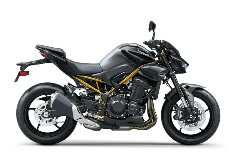 Stylowy, czarny Kawasaki Z900 z widoczną złotą ramą, gotowy na podbój dróg.