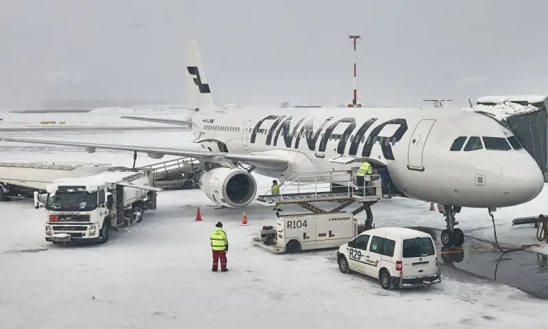 Samolot Finnair na lotnisku w śnieżny dzień. Pracownicy obsługi naziemnej przygotowują samolot do lotu. Czy do Finlandii można lecieć na dowód?