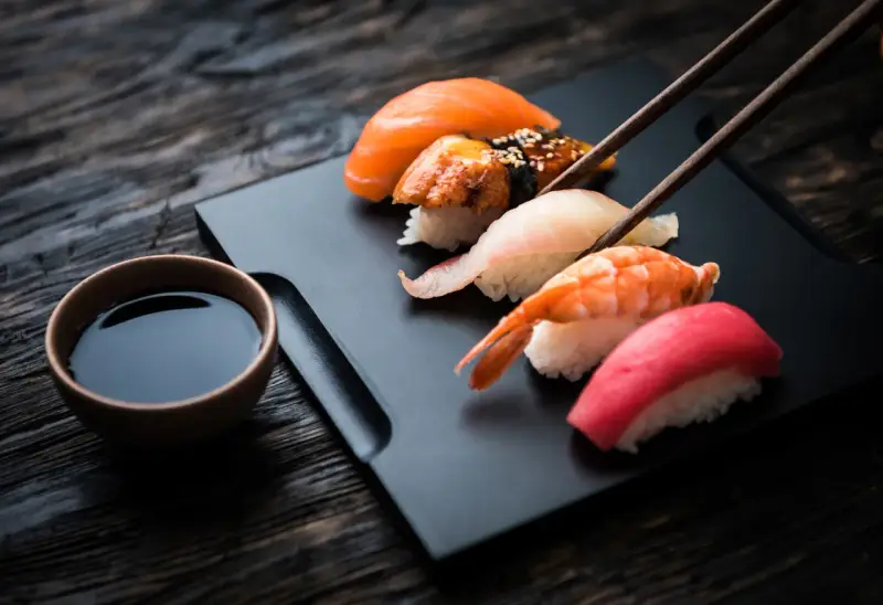 Zestaw sushi z łososiem, krewetką i tuńczykiem, gotowy do zanurzenia w sosie shoyu.