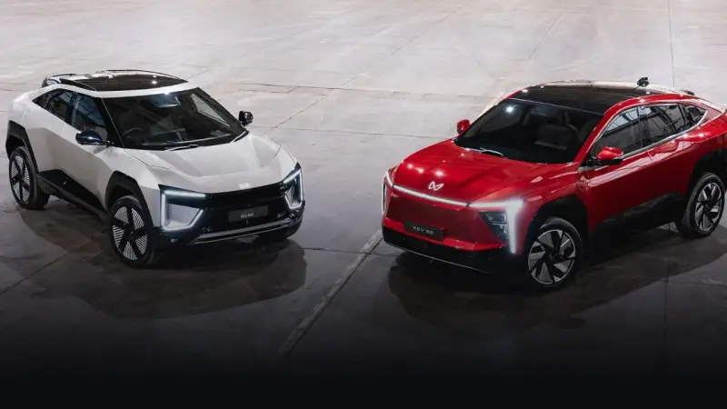 Dwa futurystyczne SUV-y, biały i czerwony, marki Mahindra, prezentują nowoczesny design z ostrymi liniami i LED-owym oświetleniem.