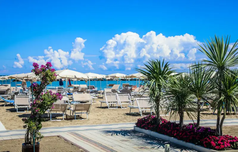 Spiaggia attrezzata con lettini e ombrelloni, palme e fiori colorati. Un'oasi di relax al Valentini Family Village, dove l'Hotel Rosalba vi aspetta.