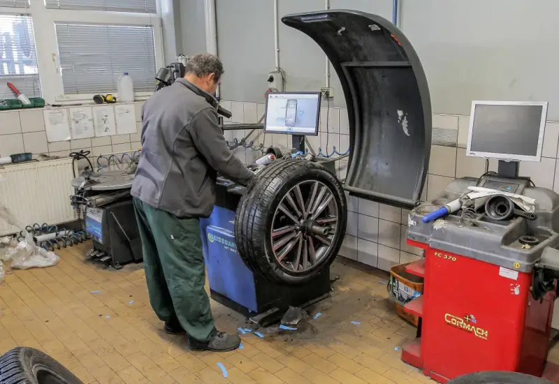 Mechanik sprawdza na maszynie, ile kosztuje wyważenie kół. Na ekranie widoczny jest schemat felgi.