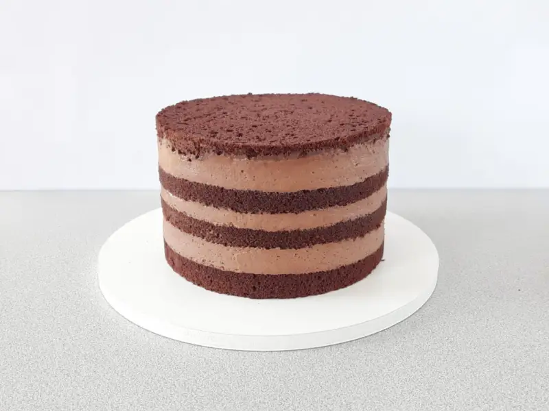 Czekoladowy naked cake z kremem, warstwy biszkoptu i kremu czekoladowego.