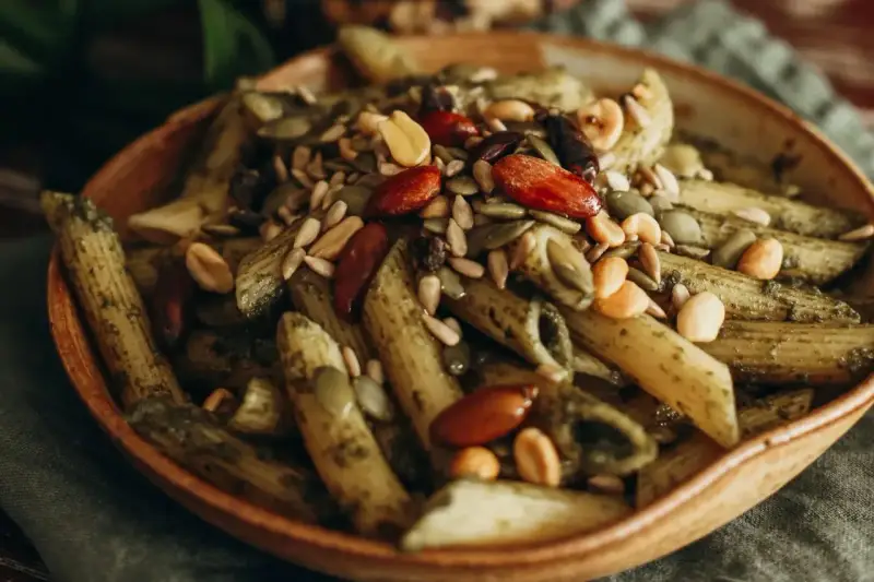 Makaron penne z zielonym pesto, posypany pestkami dyni, słonecznika, migdałami i orzeszkami ziemnymi. Idealny na dietę braci rodzeń.