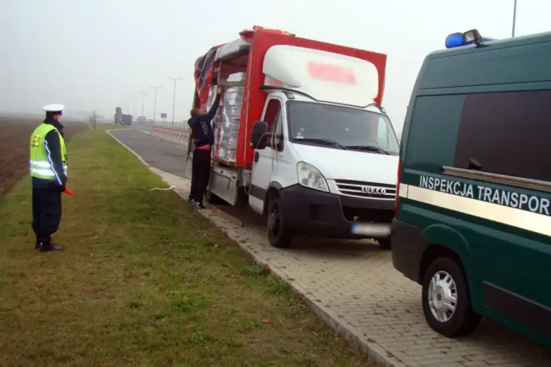 Kontrola drogowa: funkcjonariusz w kamizelce odblaskowej kieruje ruchem, obok biała ciężarówka z ładunkiem. Czy kierowca ma prawo jazdy kat b do 7,5 tony?