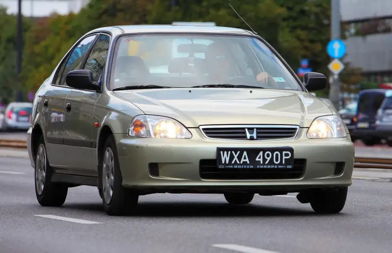 Złoty sedan Honda Civic z widocznym numerem rejestracyjnym WXA 490P. Brak tablicy rejestracyjnej z przodu.