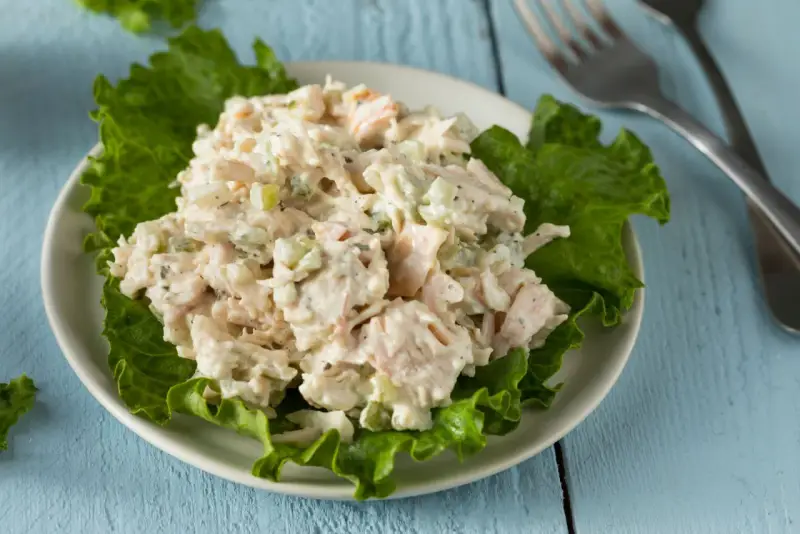 Un piatto di insalata di pollo della nonna, cremosa e ricca, servita su foglie di lattuga croccante.
