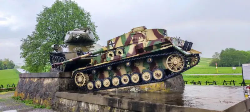 Pomnik w Dolinie Śmierci na Słowacji: dwa czołgi, jeden niemiecki w kamuflażu, drugi radziecki, stoją na kamiennym postumencie.