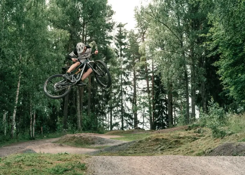 Mountainbike-åkare flyger genom luften i en skogspark nära Stockholm.